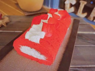 18、红丝绒蛋糕卷,最后，在蛋糕卷上挤上奶油，用玫瑰花或其它东西点缀一下，美美的红丝绒卷就完成啦！放进冰箱冷藏一下会更美味哦！