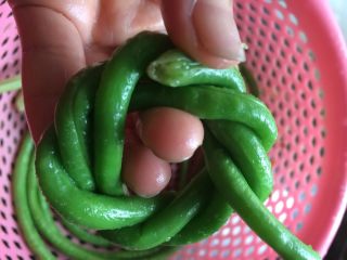 9、土豆肉末酿豆角,由于我买的豆角特别长,能够编三圈,编够三圈了,把多余的豆角,剪开(不要扔掉哦,可以炒来吃的)