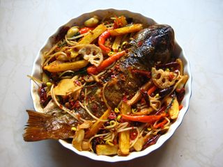 6、川香麻辣烤鱼：麻辣过瘾的豪华烤鱼,在装鱼的烤盘中先放入香菜，再依次放入煮好的干豆腐、豆芽、炸好的土豆、莲藕、连同煮料汤一起倒入烤盘中，汤汁最好多一些，以漫过鱼的1/2处为佳。
