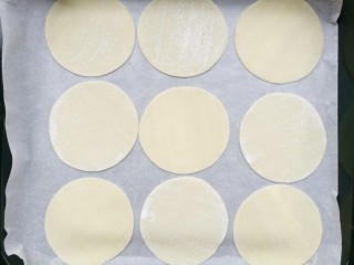 2、饺子皮辣酱饼,饺子皮平铺在铺上油纸的烤盘上。