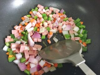 8、粗粮凤梨炒饭,加入洋葱丁、青椒丁、火腿肉丁继续翻炒。