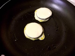 12、茄饼健康做法,调小火，放入沾了面糊的茄片。（为了照顾上学的孩子第一锅放了一滴亚麻籽油，后面的都没有放，全程无油）