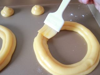 11、巴黎布列斯特泡芙,挤泡芙是下面平行挤两圈，上面再挤一圈。挤好后轻轻刷少许蛋液