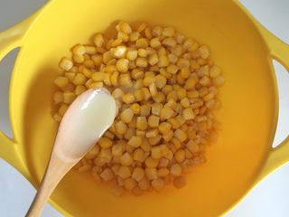 4、枸杞玉米烙,玉米粒放入碗中，用手搓成粒粒分开，加入10克炼乳和5克水，翻拌均匀。