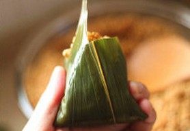 9、鲜肉棕,将粽叶由下往上翻折盖住糯米,同时侧面的粽叶翻折于内避免漏米