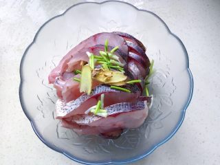 3、秘制酥鱼,把鱼肉放进容器里，撒上葱白和姜片