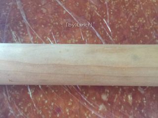 6、自制猪肉脯,盖上保鲜膜,用擀面杖擀成厚薄较均匀的薄片(不均匀的话烤时较薄的地方容易烤焦)