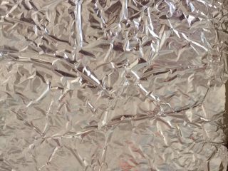 7、自制猪肉脯,然后揭掉保鲜膜,拎住对角的铝箔纸,移入烤盘。烤箱预热180度后放入,中层,烤10分钟后取出翻面