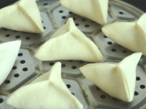 11、糖三角,做好的面胚放在刷了薄油的蒸笼上。