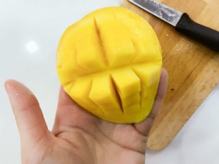 3、宝宝辅食：水果小圆子-36M ,将芒果沿果核往下切开，然后用水果刀划好十字格，划到芒果皮为止，不要把芒果皮划破哈，然后用手一顶就变成芒果花啦，接着用水果刀把果肉刮下来就好啦。