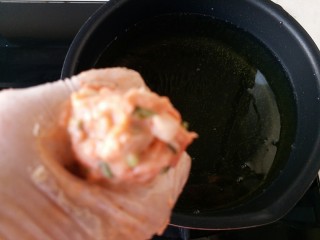 16、胡萝卜香菜素丸子,将做丸子的材料抓入手中,用虎口挤出里面的丸子生料成圆圆的球形,就可以入油锅里炸了