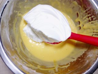 9、小四卷(后蛋法）,把三分之一蛋白霜加入蛋黄糊里用蛋抽或刮刀以从下往上翻拌手法翻拌均匀，避免消泡。