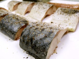 5、盐煎青花鱼,用手指一小撮一小撮捏着海盐，均匀地洒在鱼块表面，再用研磨瓶均匀地撒上黑胡椒碎。