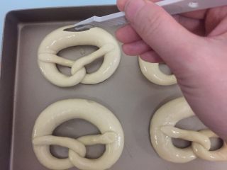 10、德国碱水面包普雷结,沥干水放在烤盘上,烤箱预热195度10分钟,粗处用刀片割口