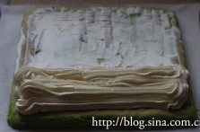 12、菠菜奶油蛋糕卷,取一张油纸，铺于案板上，将蛋糕片底面朝上，抹上奶油。