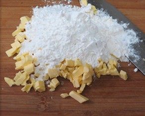 2、肉桂苹果派,混合高粉、低粉和盐,倒在黄油丁上,用刀切至黄油和粉类变成松散的沙粒状