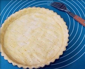 6、肉桂苹果派,铺在派盘上,用手轻轻按一下四边,然后用擀面杖沿着边缘擀掉多余的面皮。用叉子在派皮上扎一些孔