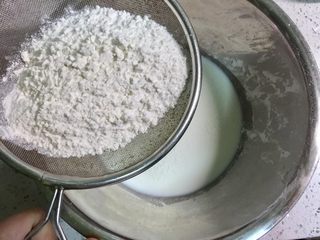 2、无油原味松饼,不锈钢盆里倒入牛奶，筛入低筋面粉，为了做出蓬松的口感，面粉要用低筋的，用橡皮刀把低筋面粉和牛奶混合均匀备用。