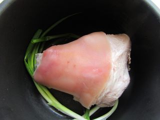 6、卤蹄髈,再次电压力锅或电饭煲刷干净，铺上葱和姜片，放入蹄艕
