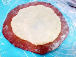 12、心相印红丝绒麻薯软欧,手沾粉或油取一份麻薯,拉开均勻铺在面团上。