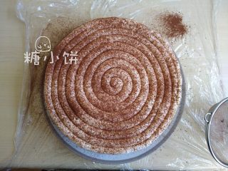 9、【奥利奥冻芝士蛋糕】,把打发的淡奶油以圈形挤在表面(如图),再撒上可可粉装饰即可