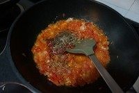 6、黑橄榄培根虾仁披萨,中火炒，看见番茄出水，陆续加入黑胡椒、牛至叶、糖、盐，翻炒一下盖上盖焖一下，令番茄更烂，洋葱更软。