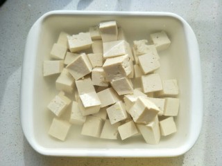 2、麻婆豆腐,盆里倒入热水，加适量的盐，把豆腐切块浸泡。