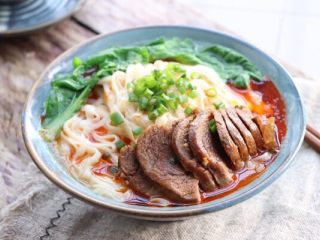12、牛肉面,放上卤好的牛肉，加一勺卤汁2勺面条汤；青菜叶过水捞出摆碗里，淋上辣油撒葱花即可开吃！一碗热乎乎的香辣牛肉面来啦！
