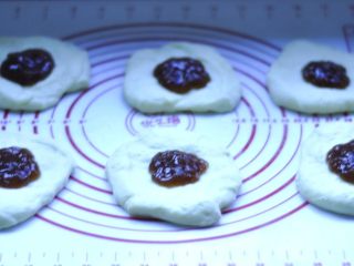 5、软欧包,将每一份都按扁，包入草莓果酱，收口朝下