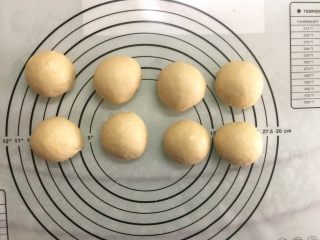7、椰蓉面包小卷,将面团取出排气后平均分割成8份，滚圆盖上保鲜膜松弛15分钟。