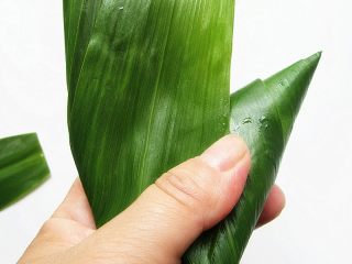 9、花生腊肠粽,把叶子折过来,按顺方向围着粽子身体转一圈包紧