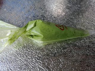 15、抹茶波点蛋糕卷,装入裱花袋。烤箱预热上下火175度10分钟。