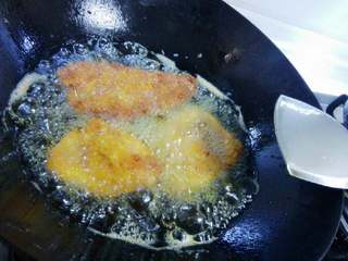 4、猪排饭,最后放油锅里炸,表面炸定型后转中小火炸,确保猪排炸熟透,最后转大火将表面炸至金黄时捞出控油。