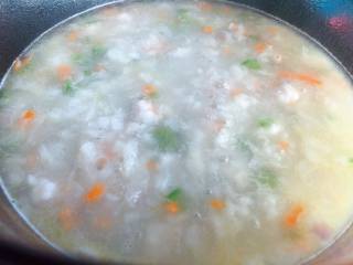 8、【宝宝辅食】鲜虾疙瘩汤,锅里水沸腾后，火关小一点，保持沸腾就可以，把搅拌好的面絮倒进去，左手端面碗，右手拿筷子一边搅拌一边往锅里撒
