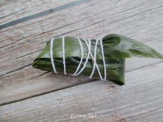 6、红糖红豆蜜枣粽,把粽子盖上，用大拇指按住，包好后用绳捆起来