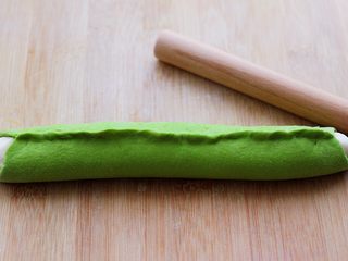 13、翡翠白玉生煎包,然后把绿色面皮包住白色长条，把边边用手捏紧。