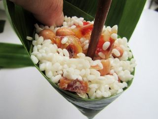 8、花生腊肠粽,放入糯米，装满后用筷子上下插几下，压一压，这样可以让粽子形状更饱满