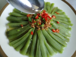 13、蒜蓉蒸丝瓜,将辣椒和香葱放到蒸熟的丝瓜上面。用炒锅将油烧热，将热油浇到辣椒上。