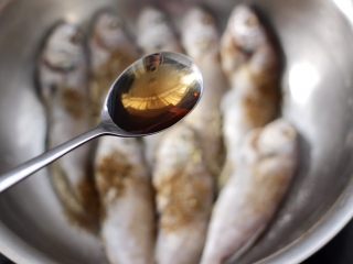 8、五香干炸大头宝鱼,再倒入料酒去腥味。