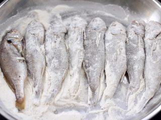 10、五香干炸大头宝鱼,把腌制好的大头鱼，裹上一层薄薄的面粉。