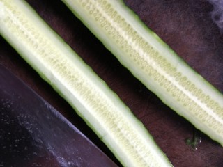 3、凉拌拍黄瓜,对半切开,拿刀的侧面轻轻拍黄瓜至微扁。