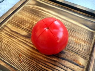 5、宝宝餐 番茄丝瓜补钙粥,番茄清洗干净，在顶部划一个十字。