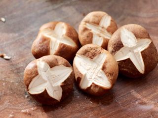 2、年夜饭必备的香菇油菜,把洗净的香菇开始改花刀，在香菇的中间先改一刀，再横切一刀，成为十字形状，给所有的香菇改好刀后。