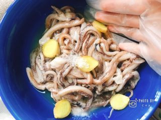 1、再也不用出门去排队买的香辣鱿鱼须(烤箱版),鱿鱼须洗净沥干水分,依次倒入料酒、姜片、盐,戴上一次性手套混合均匀。