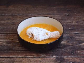 11、烤奥尔良风味黄金鸡腿,再放入蛋液器具中，两面浸泡30秒，使鸡腿均匀粘满蛋液。