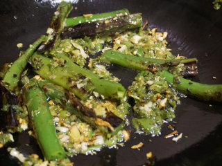 6、烧椒茄子,然后下烧椒节和烧椒碎略炒，放少量清水，加酱油、白糖、盐调味