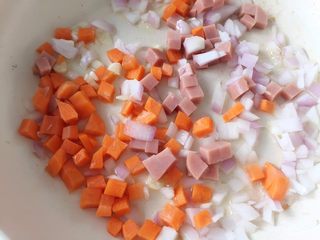 6、虾仁菠萝炒饭,重新热锅，加适当橄榄油，加入火腿丁、洋葱、胡萝卜丁翻炒均匀，中火2分钟左右稍稍变色（大人吃可以先下蒜末爆香）