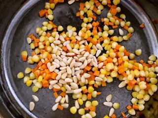 9、颜值爆表的 松仁玉米番茄盅,加入松仁,白糖炒匀