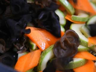 3、这道菜上桌朋友都爱吃，关键做法还简单易学,放入西葫芦、胡萝卜、木耳翻炒片刻。