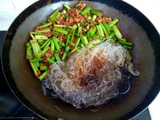 11、西芹肉沫烧粉丝,把肉沫西芹铲到一边,放入粉丝,在粉丝上放入两勺生抽,半碗清水